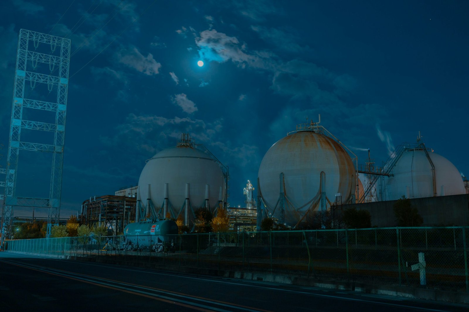 a full moon is seen over a large industrial area