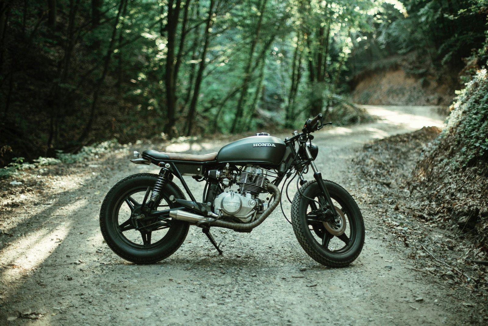 motorcycle parks on road between trees, Off-Road Small Vehicles