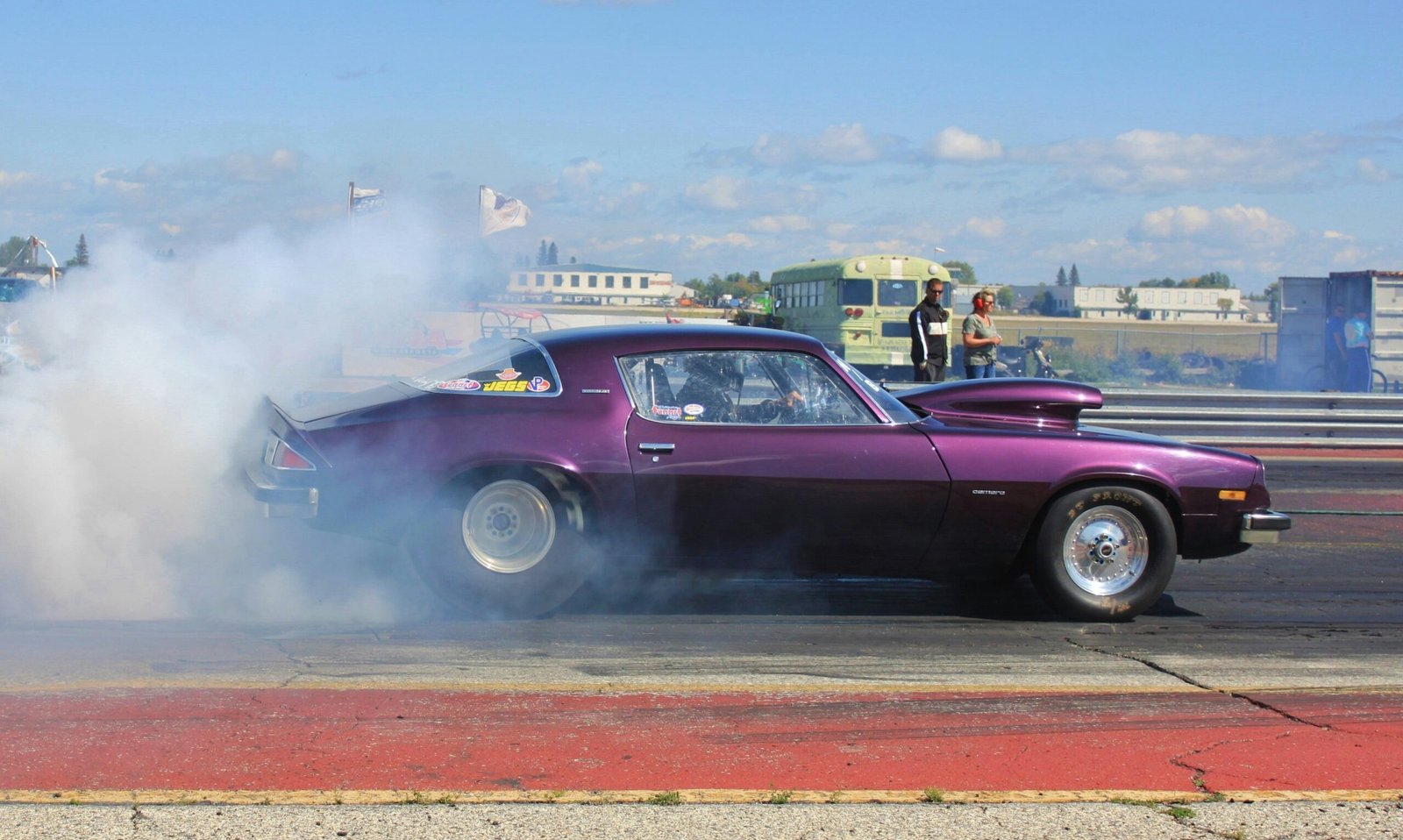 purple coupe burning out on road during daytime